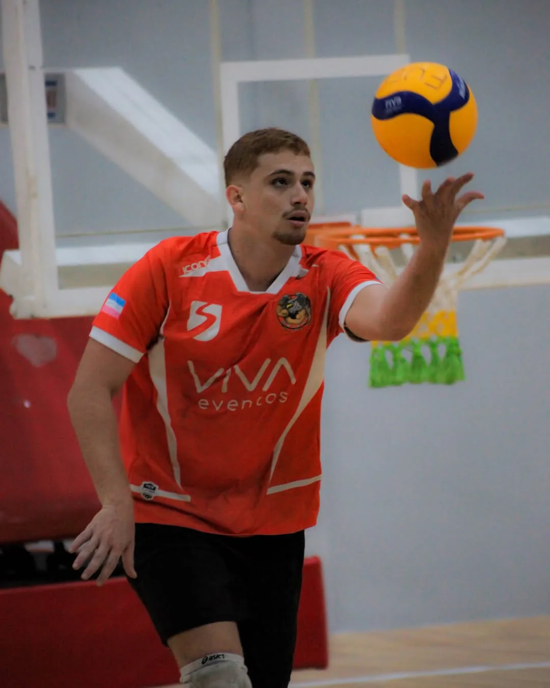 Jogador de camisa laranja tocando a bola com a ponta dos dedos