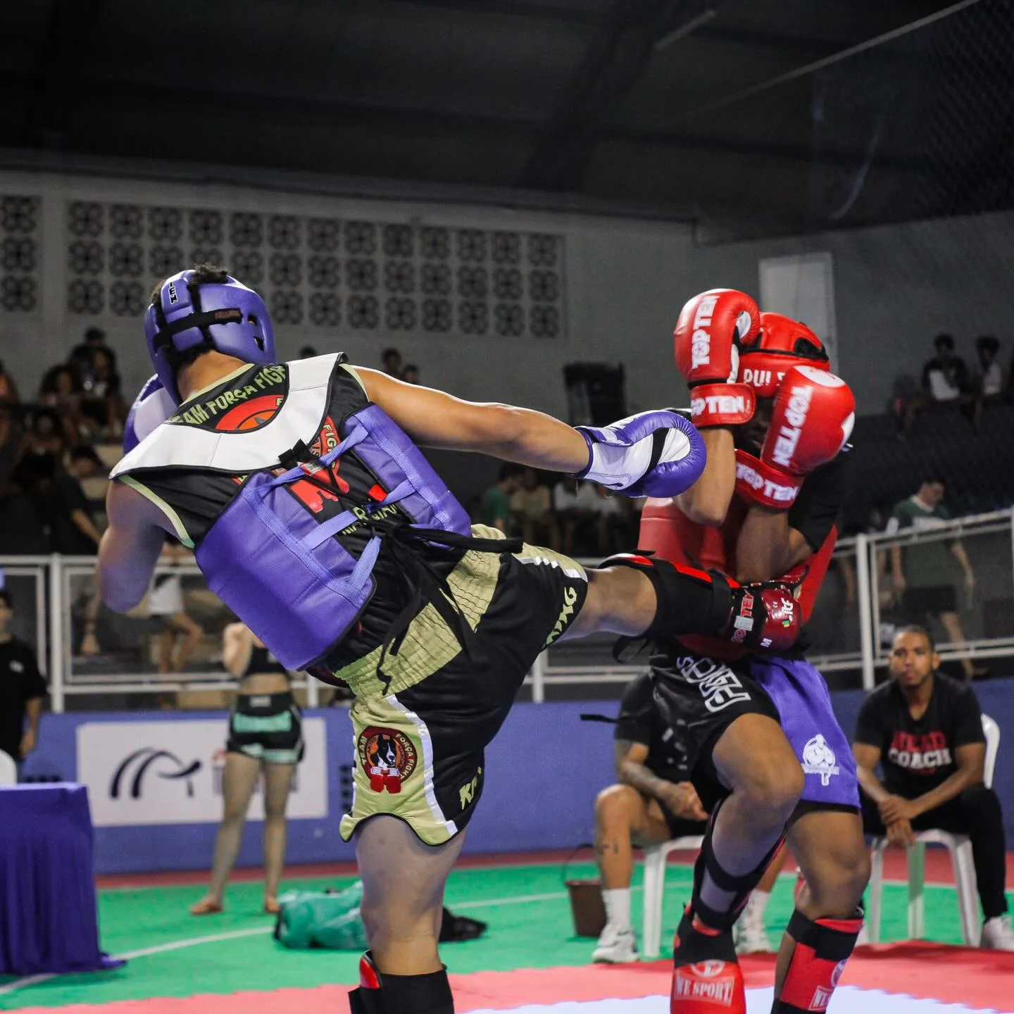 Lutadores de capacete roxo e vermelho trocando golpes