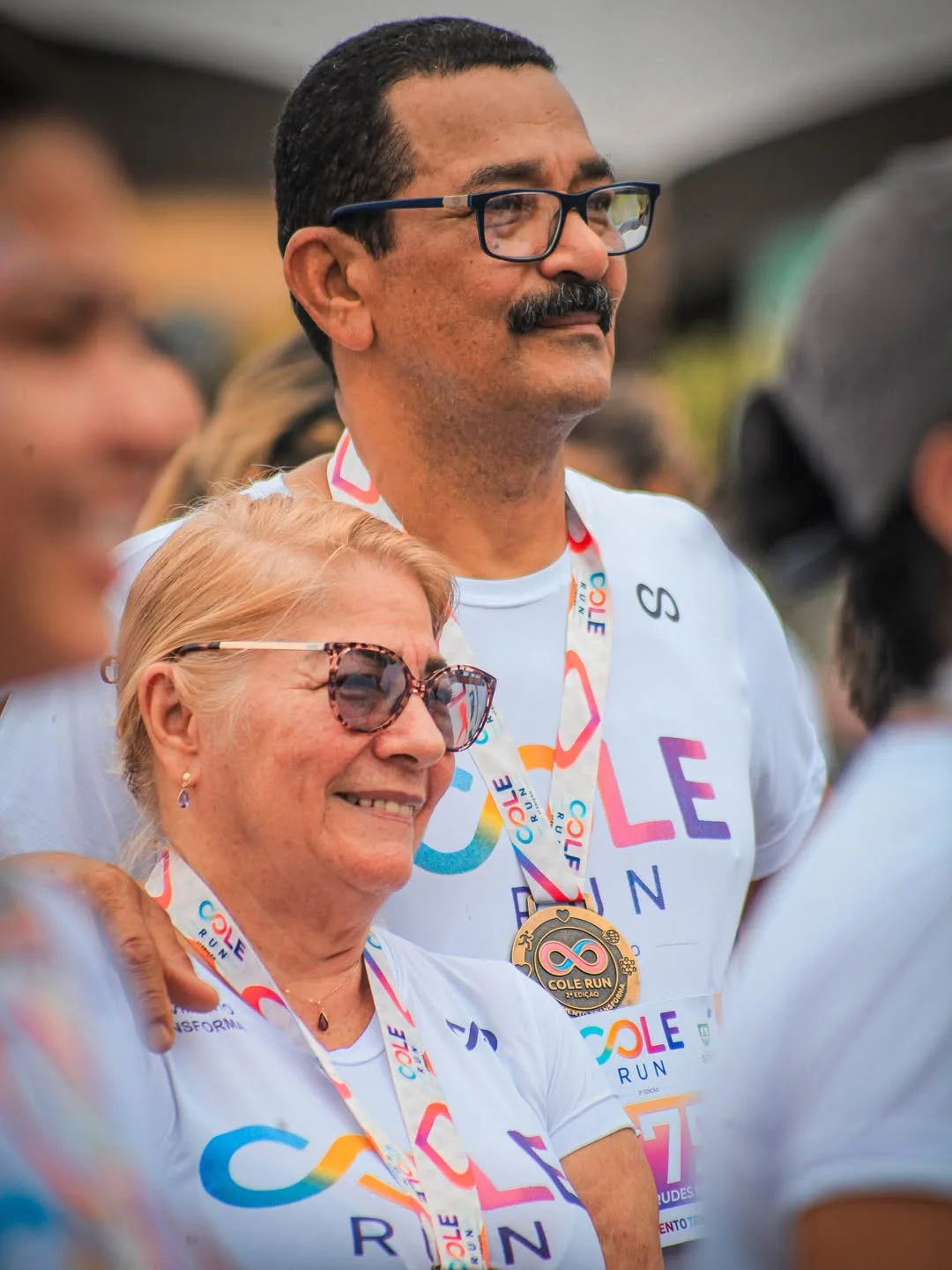 Casal sorrindo com medalhas no pescoço