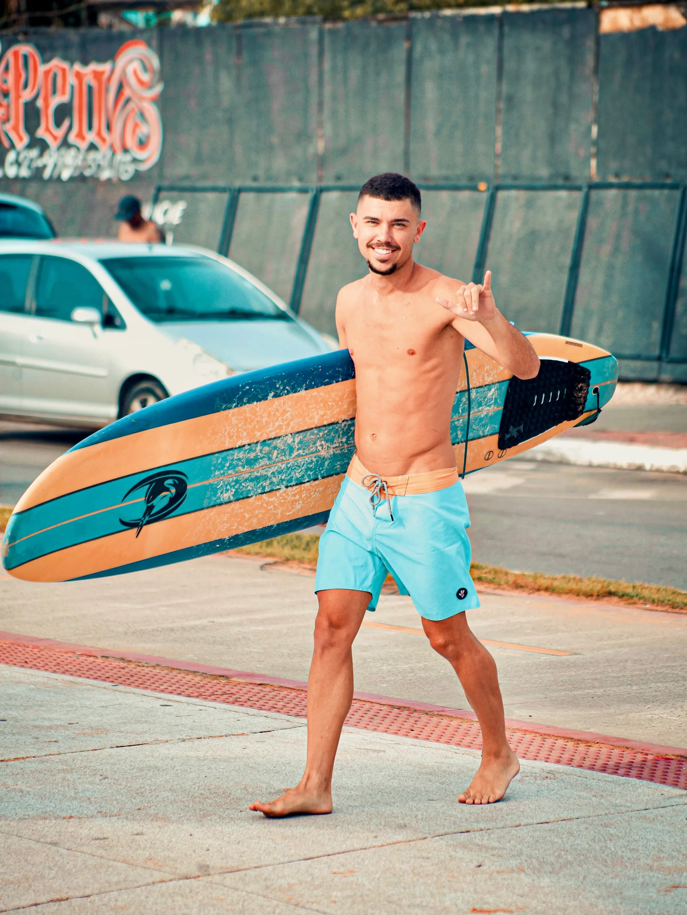 Surfista sorrindo na faixa de pedestres com a prancha