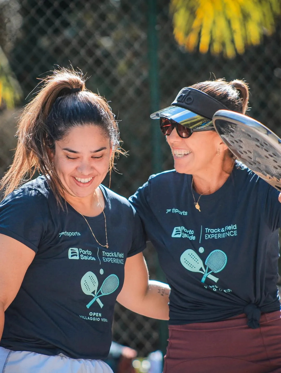 Duas jogadoras sorrindo com raquetes de beach tennis