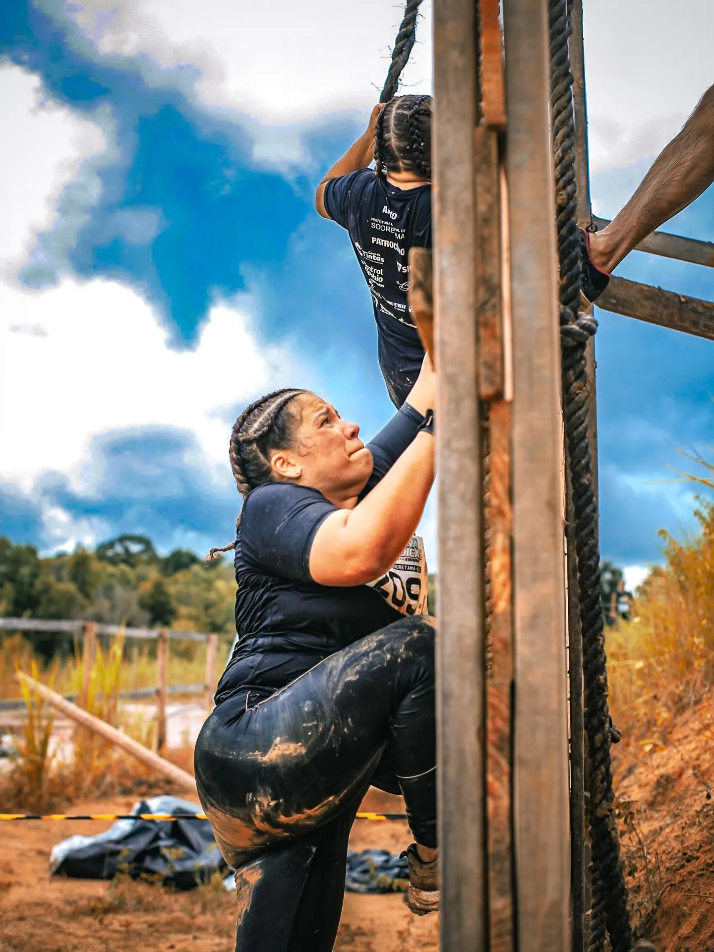 Participante escalando uma parede de madeira com corda