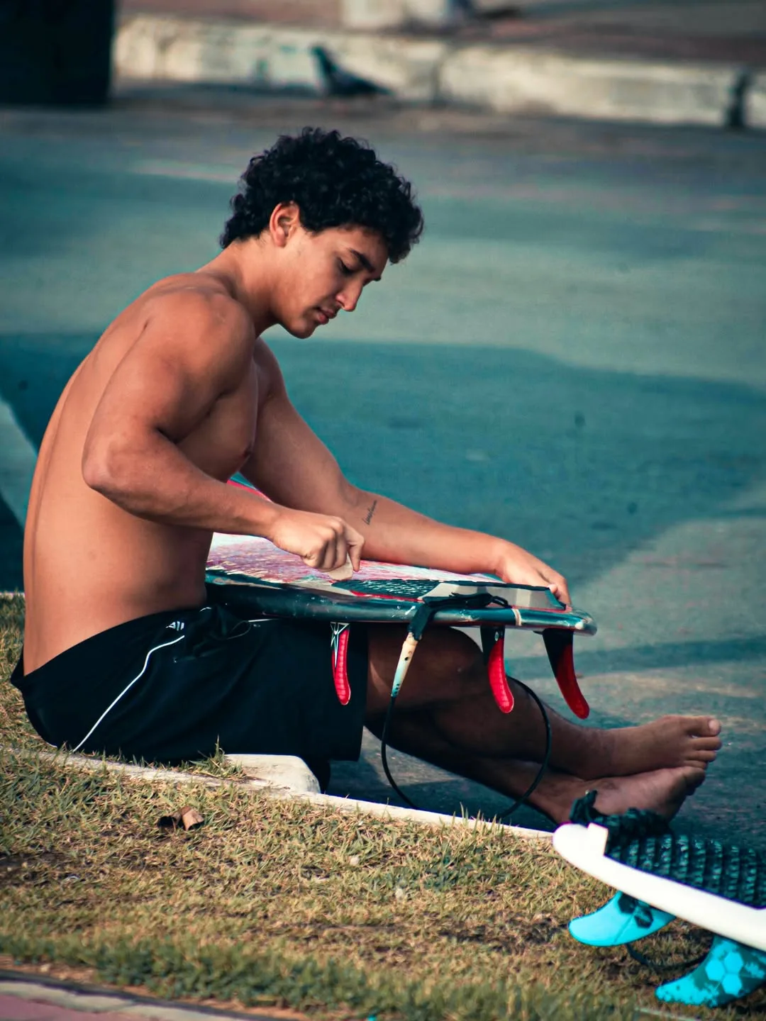 Surfista sentado preparando a prancha