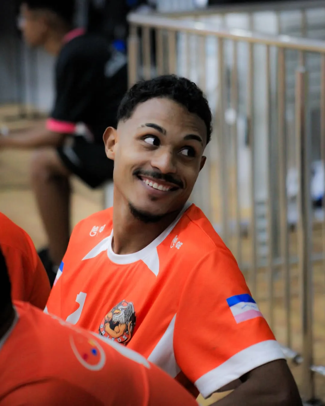 Jogador de camisa laranja sorrindo