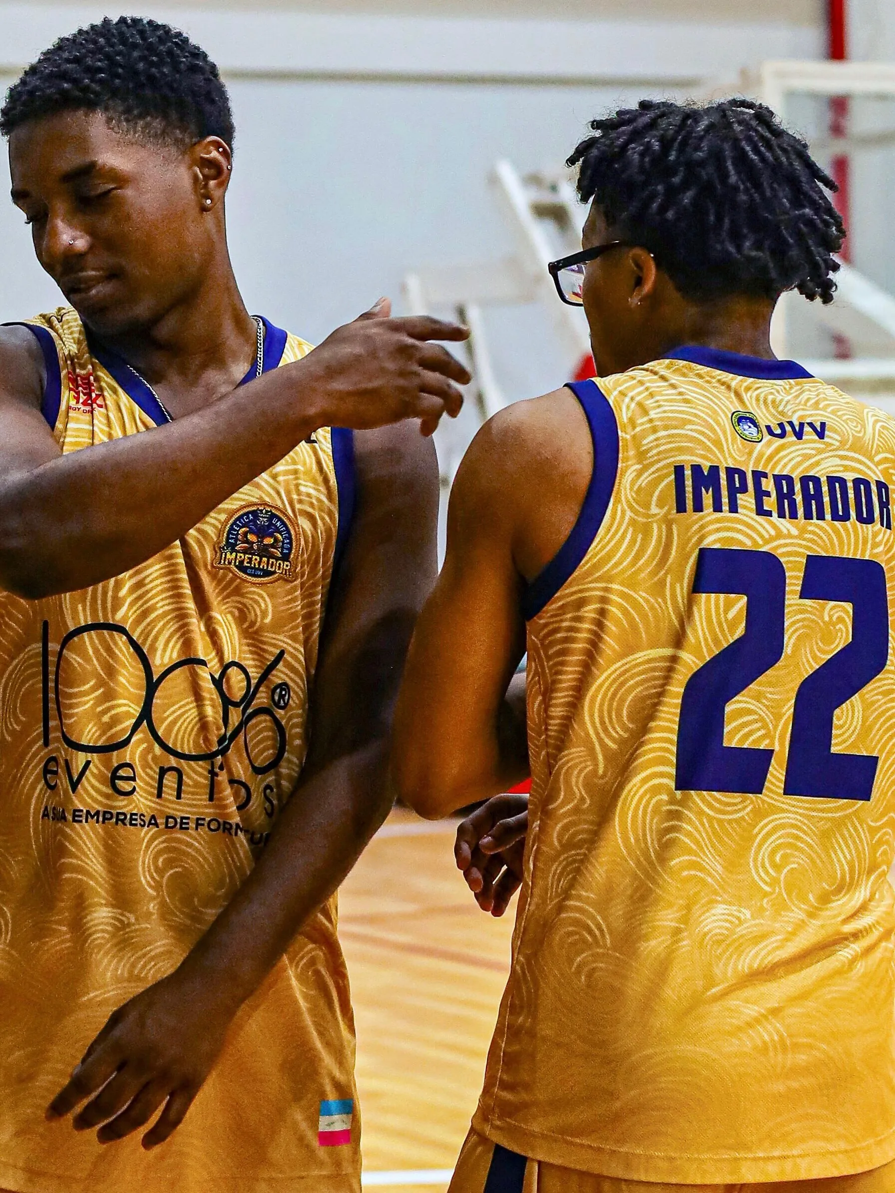 Dois jogadores de uniforme amarelo conversando em quadra