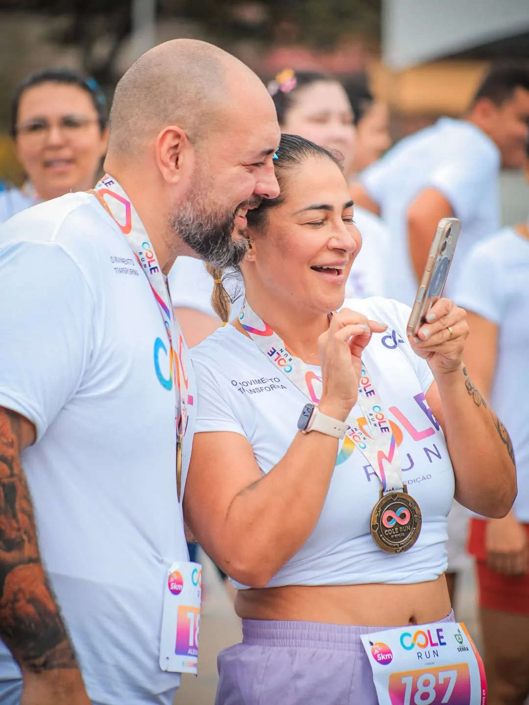 Casal de participantes com medalhas fazendo uma foto com o celular