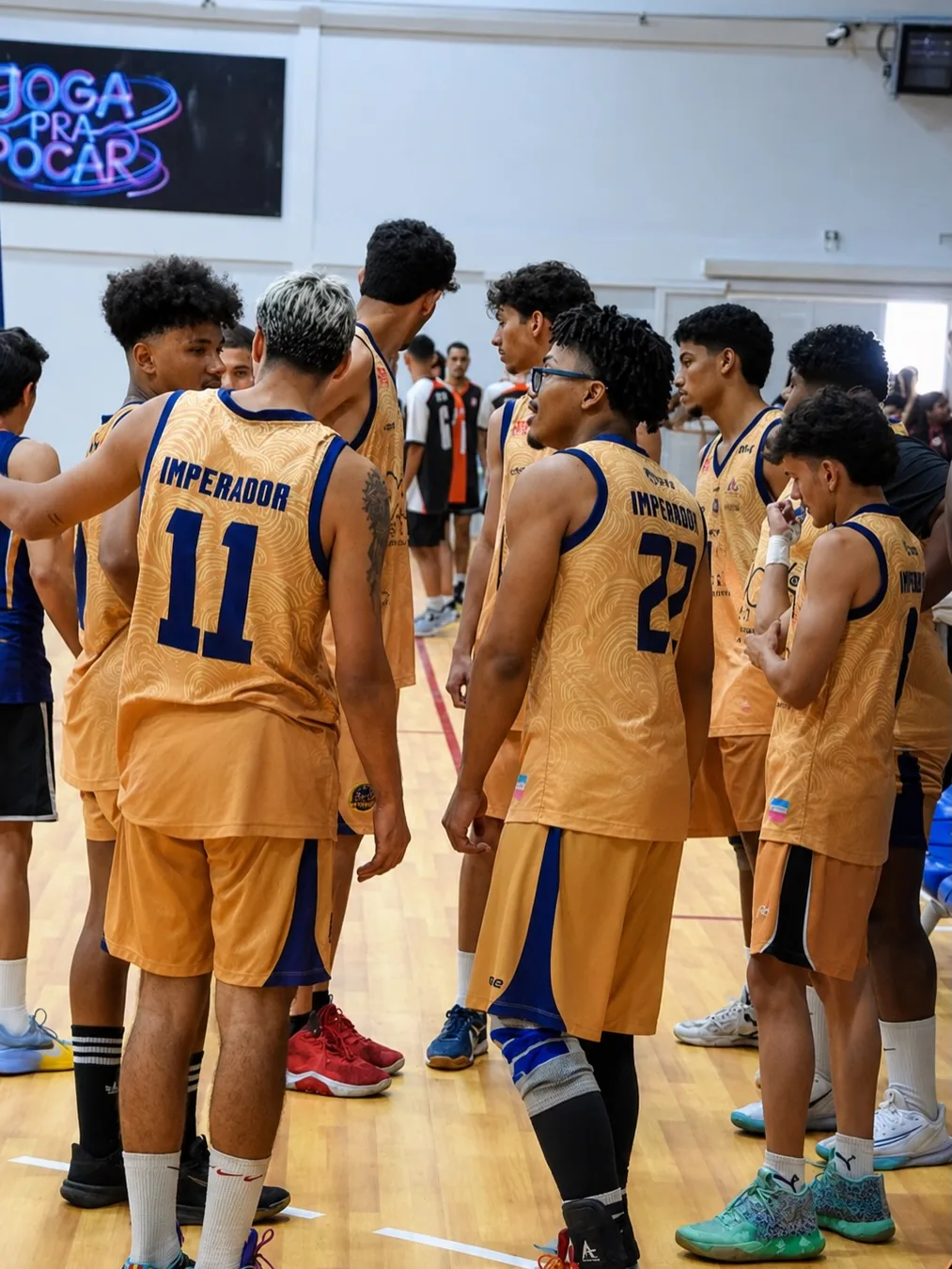 Equipe de uniforme amarelo reunida em quadra