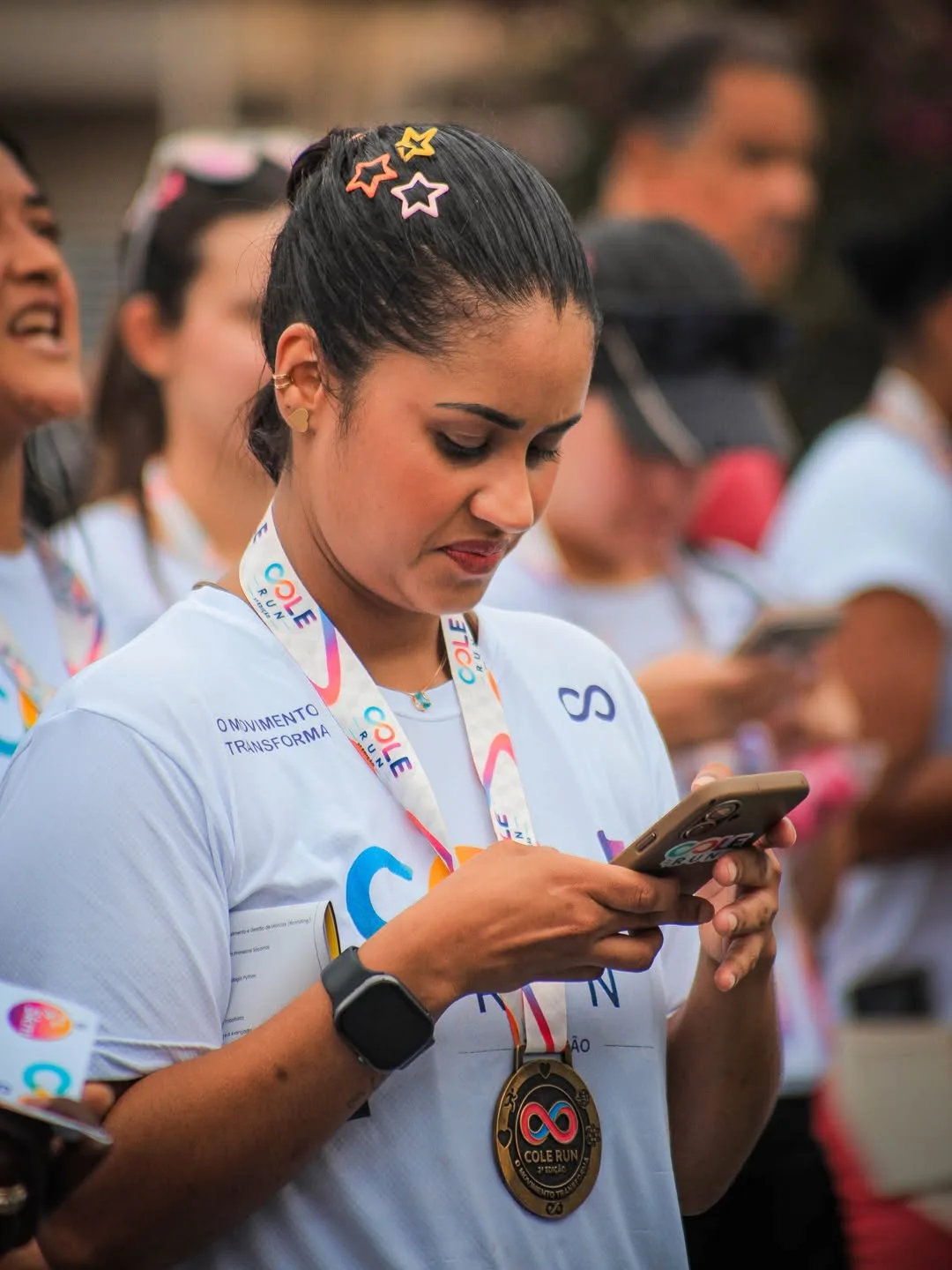 Participante com medalha olhando o celular