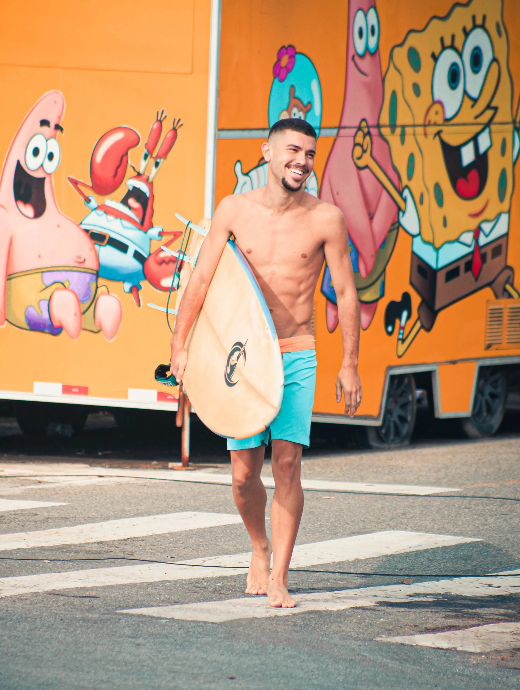 Surfista com a prancha diante de um food truck colorido