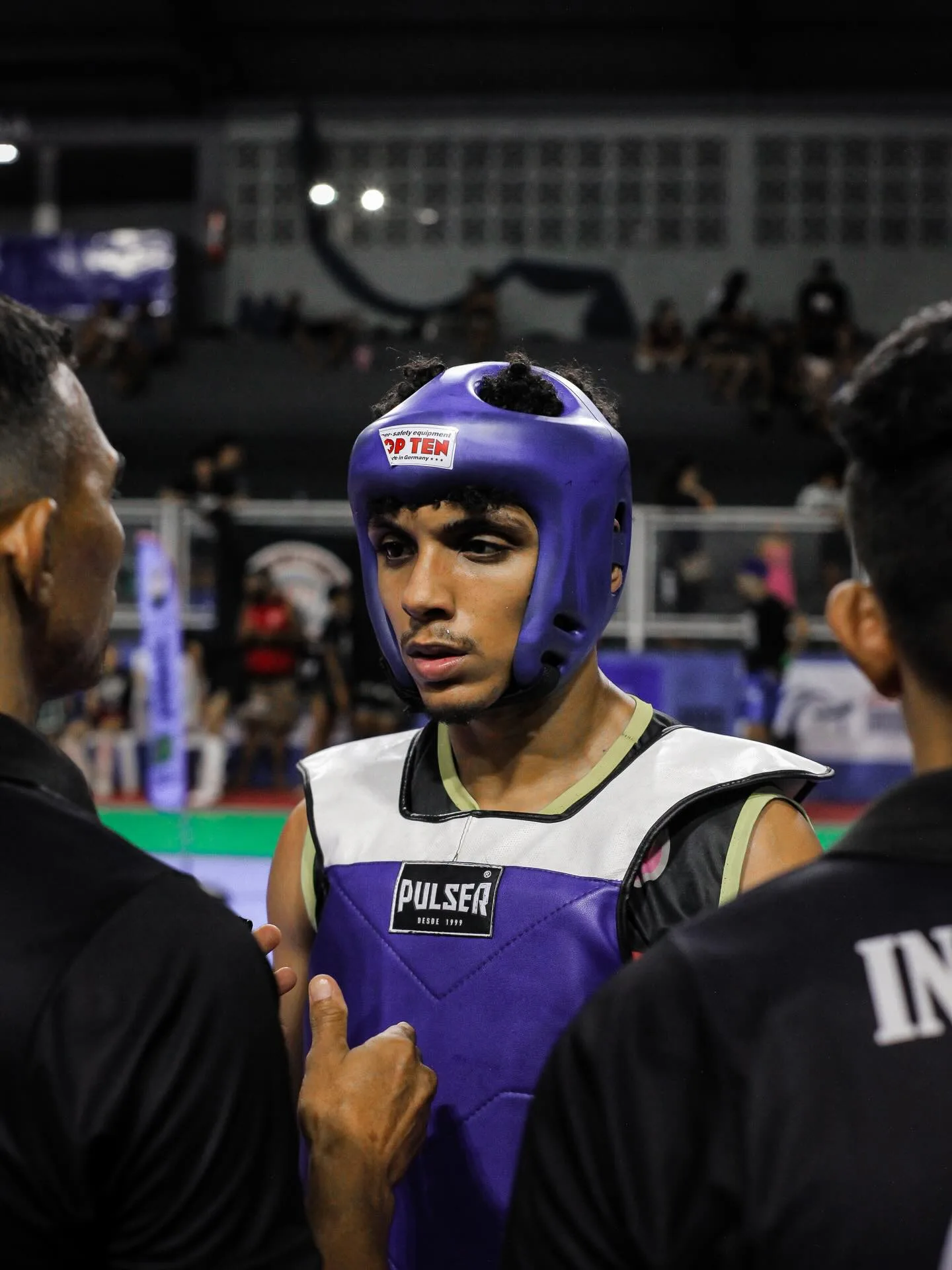 Lutador de capacete roxo cercado pela equipe
