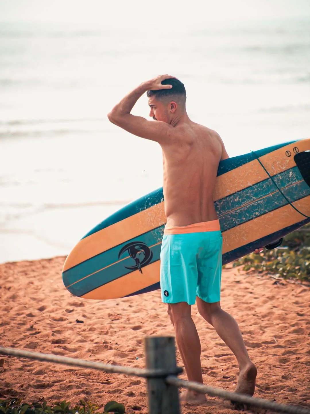 Surfista na areia com a prancha debaixo do braço