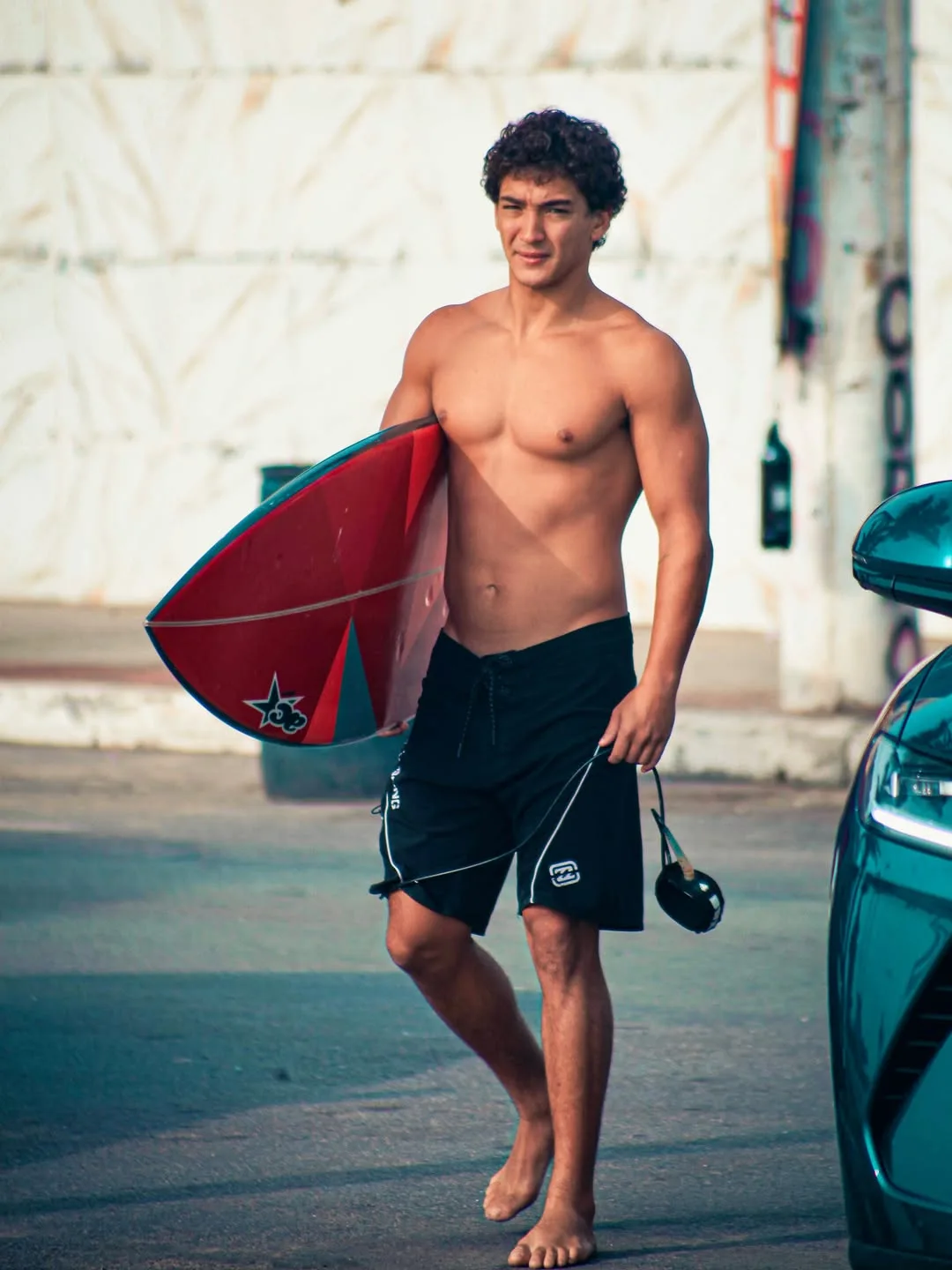 Surfista caminhando com uma prancha vermelha