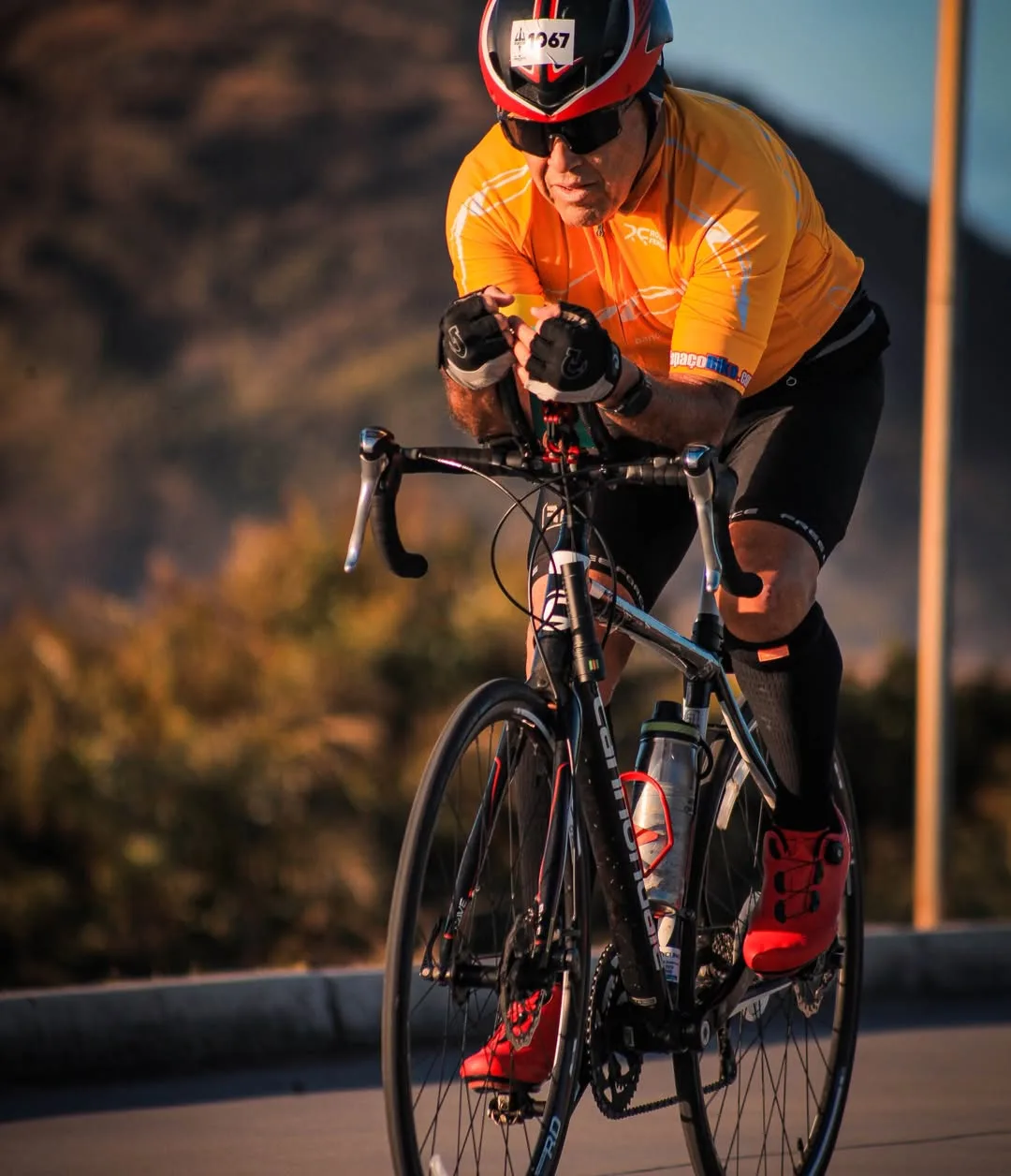 Ciclista de camisa laranja e capacete em bicicleta de estrada