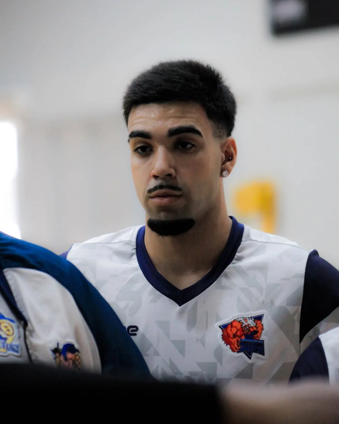 Jogador de uniforme branco olhando para baixo