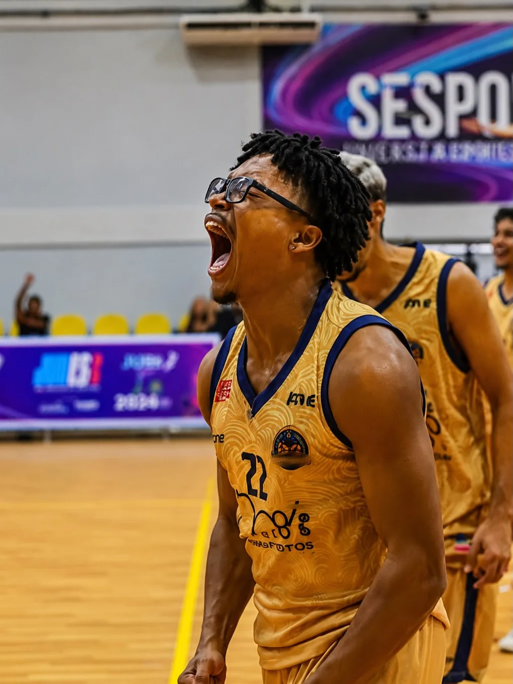 Jogador de uniforme amarelo gritando em comemoração na quadra